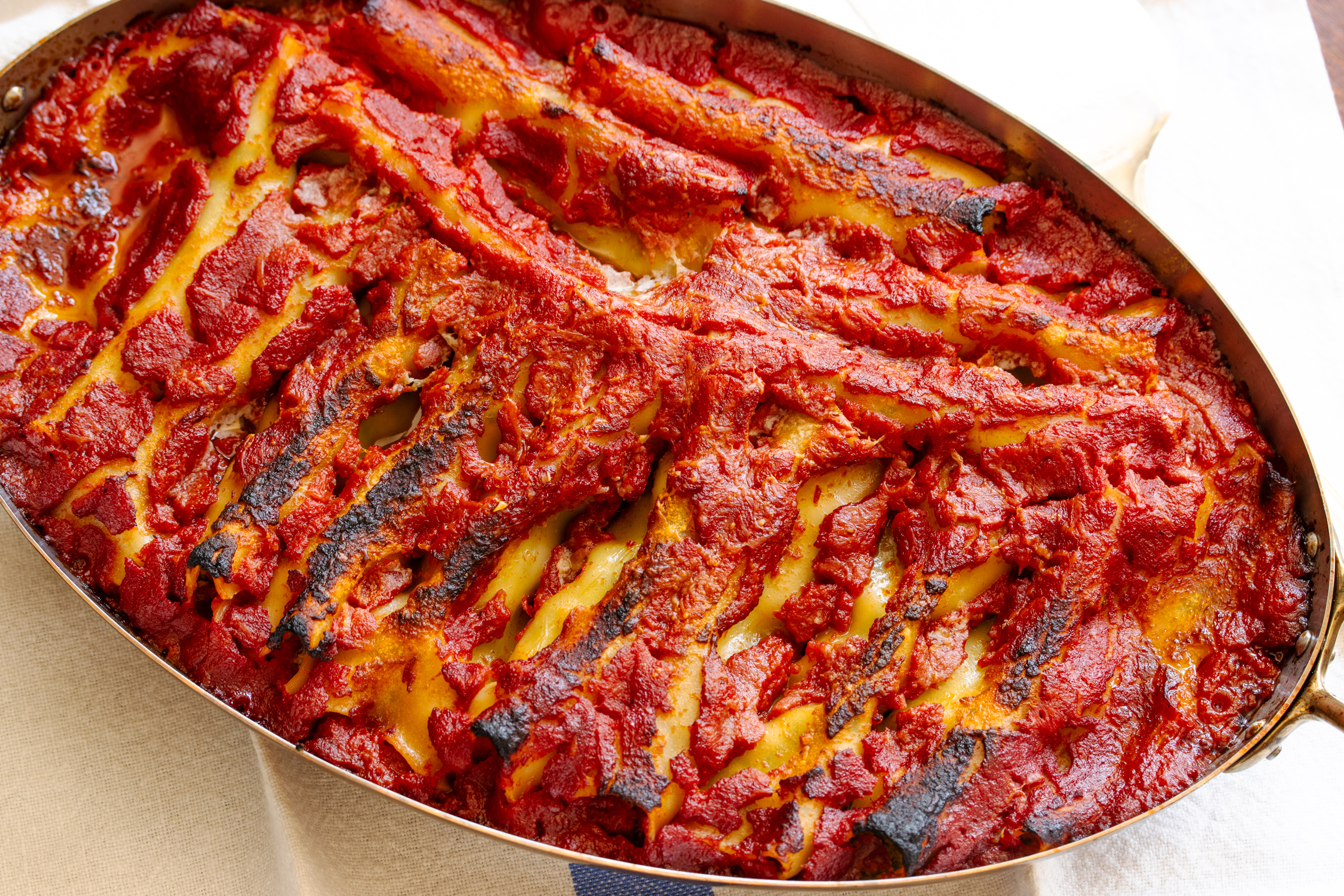 Cannelloni out of the oven in an oval baking dish.