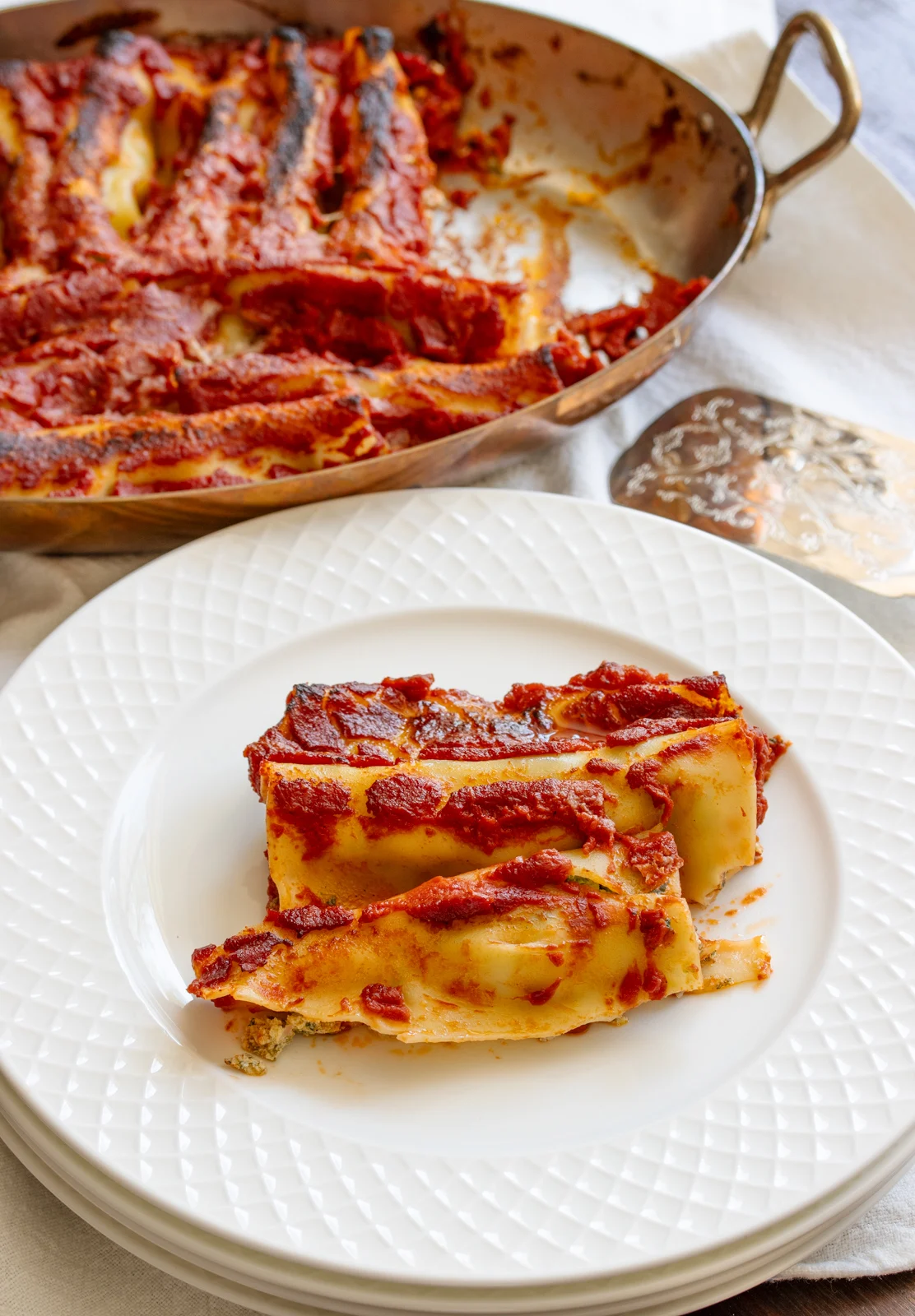 Spinach and ricotta cannelloni served in a white plate.