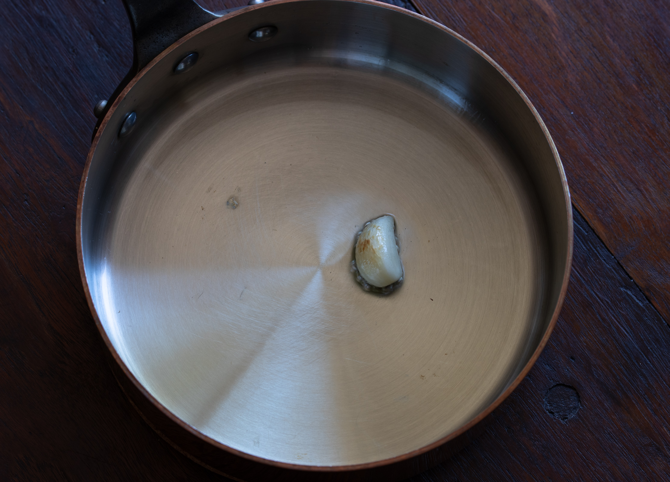 Garlic clove cooking wiht oil in a pot>