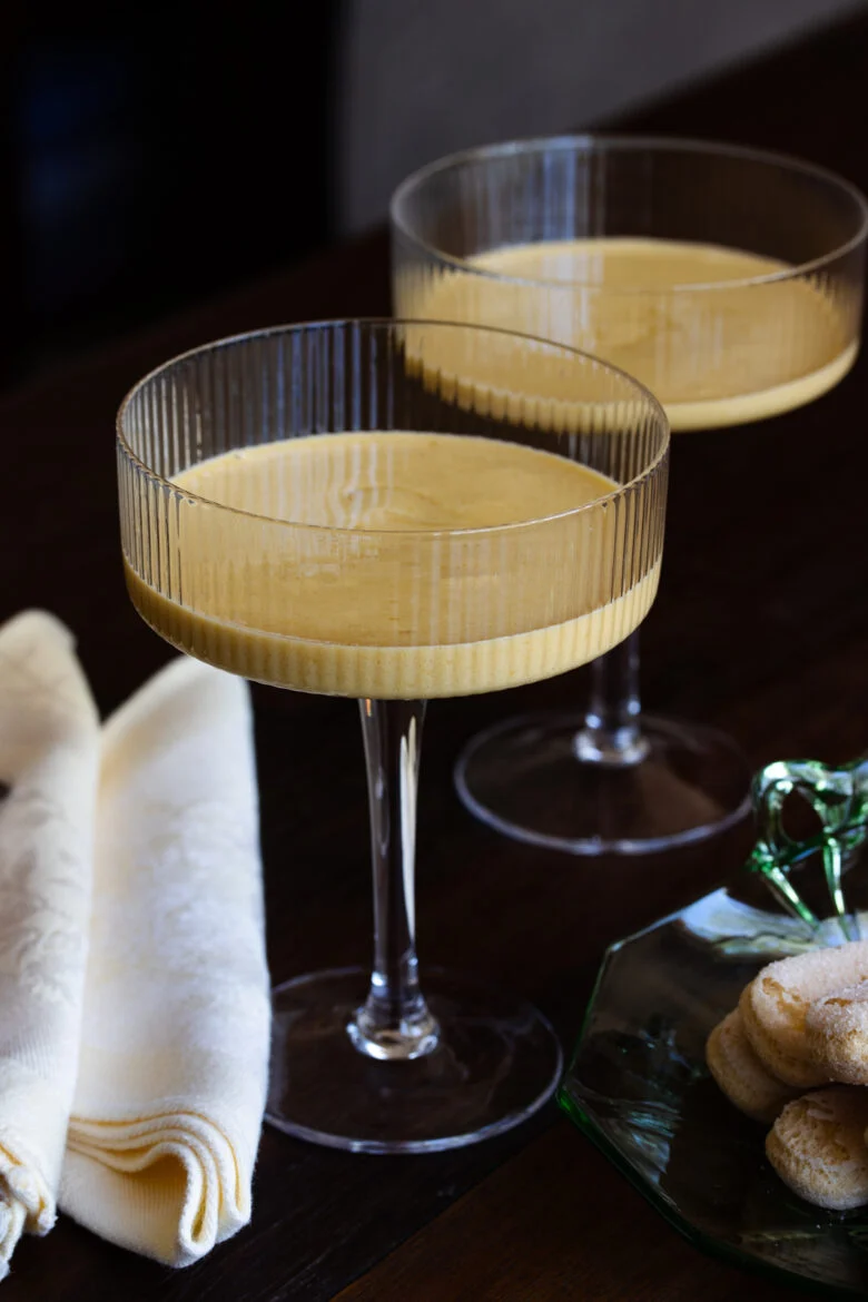 Zabaglione served in a couple glass with savoiardi cookies next to them.