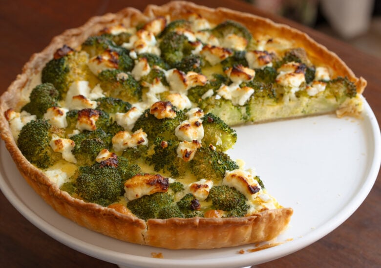 Baked broccoli quiche on a serving platter with a slice removed.