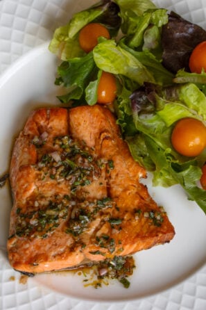 Tarragon sauce over the broiled salmon served in a plate with a side order of green salad.
