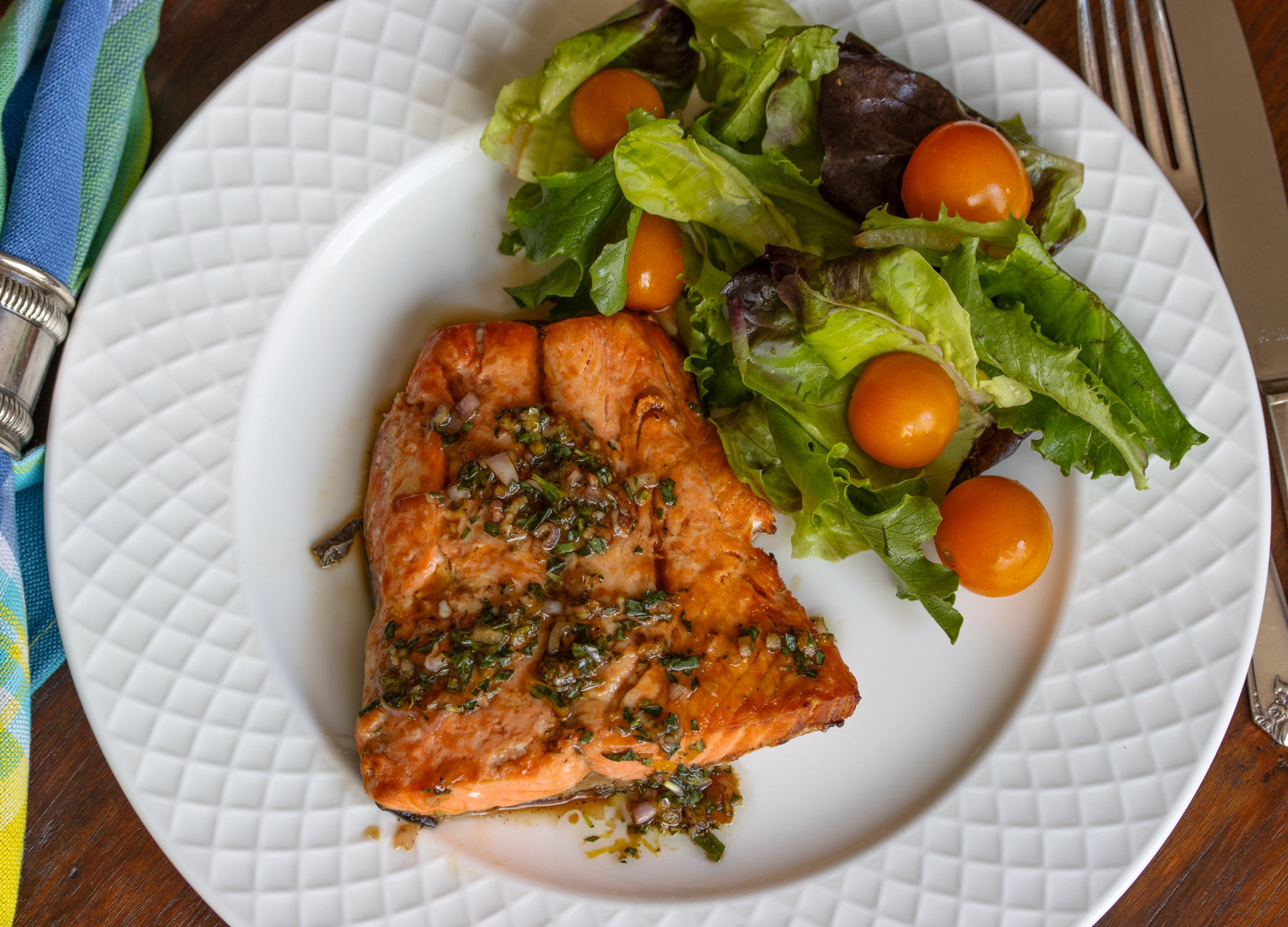 Tarragon sauce over the broiled salmon served in a plate with a side order of green salad.