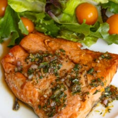 Broiled salmon with tarragon sauce surrounded by salad.