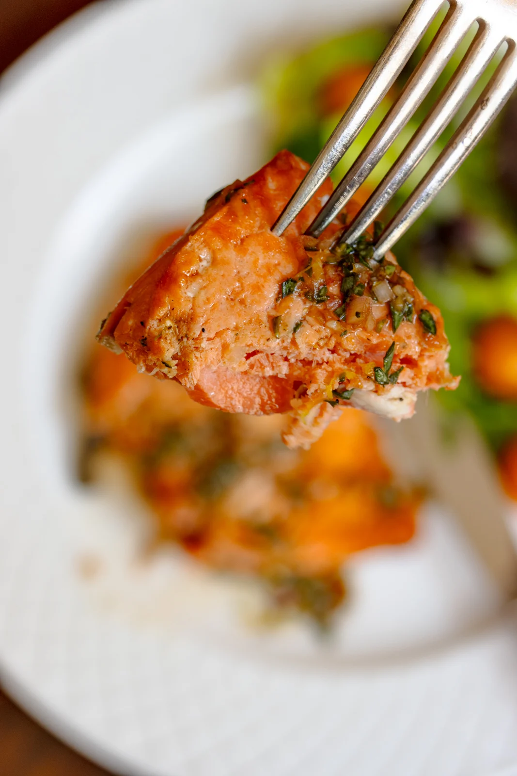 A fork with a serving bite size salmon close up.