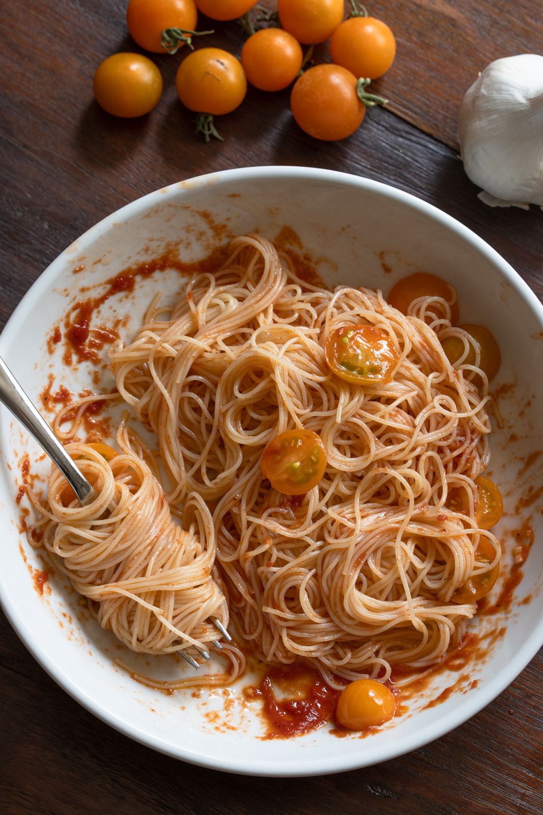 Angel hair pasta with the reduced tomato puree in a white serving plate. 