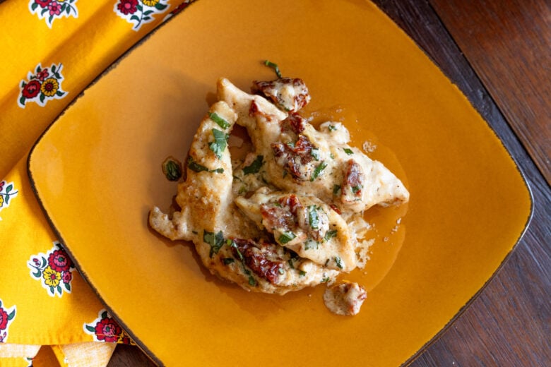 Chicken served on a ocre color plate with a yellow napkin.