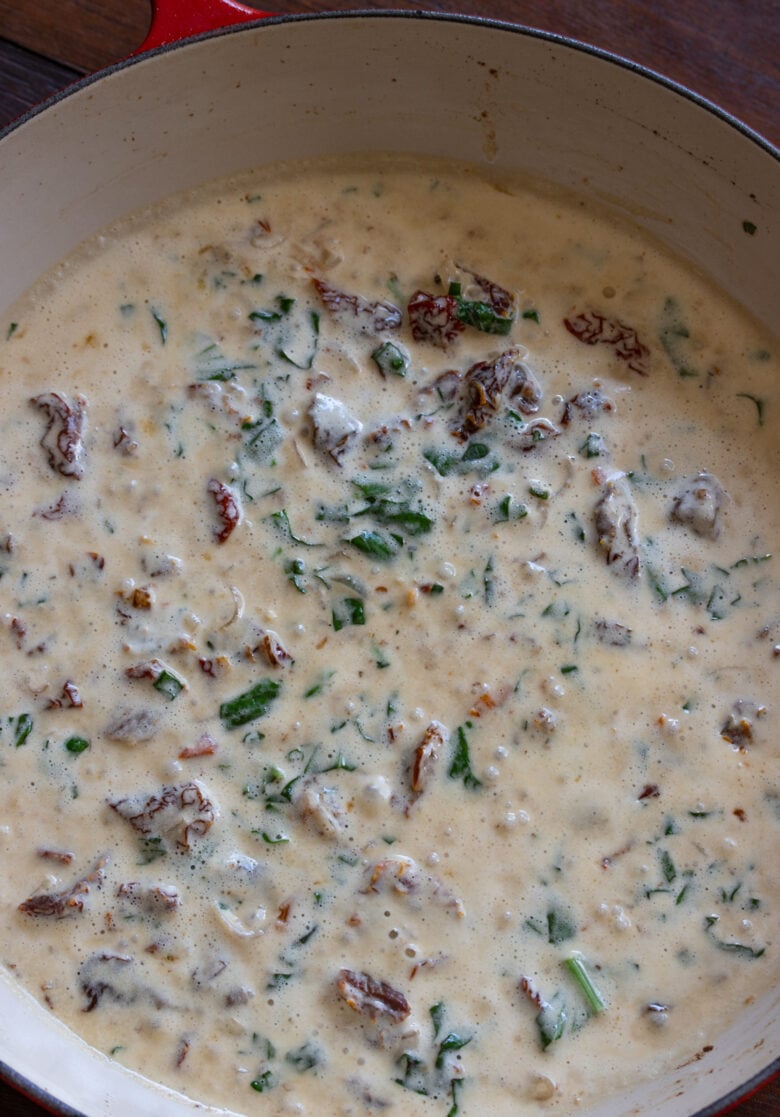 Heavy cream, sun dried tomatoes and basil added to the chicken in a large skillet. 