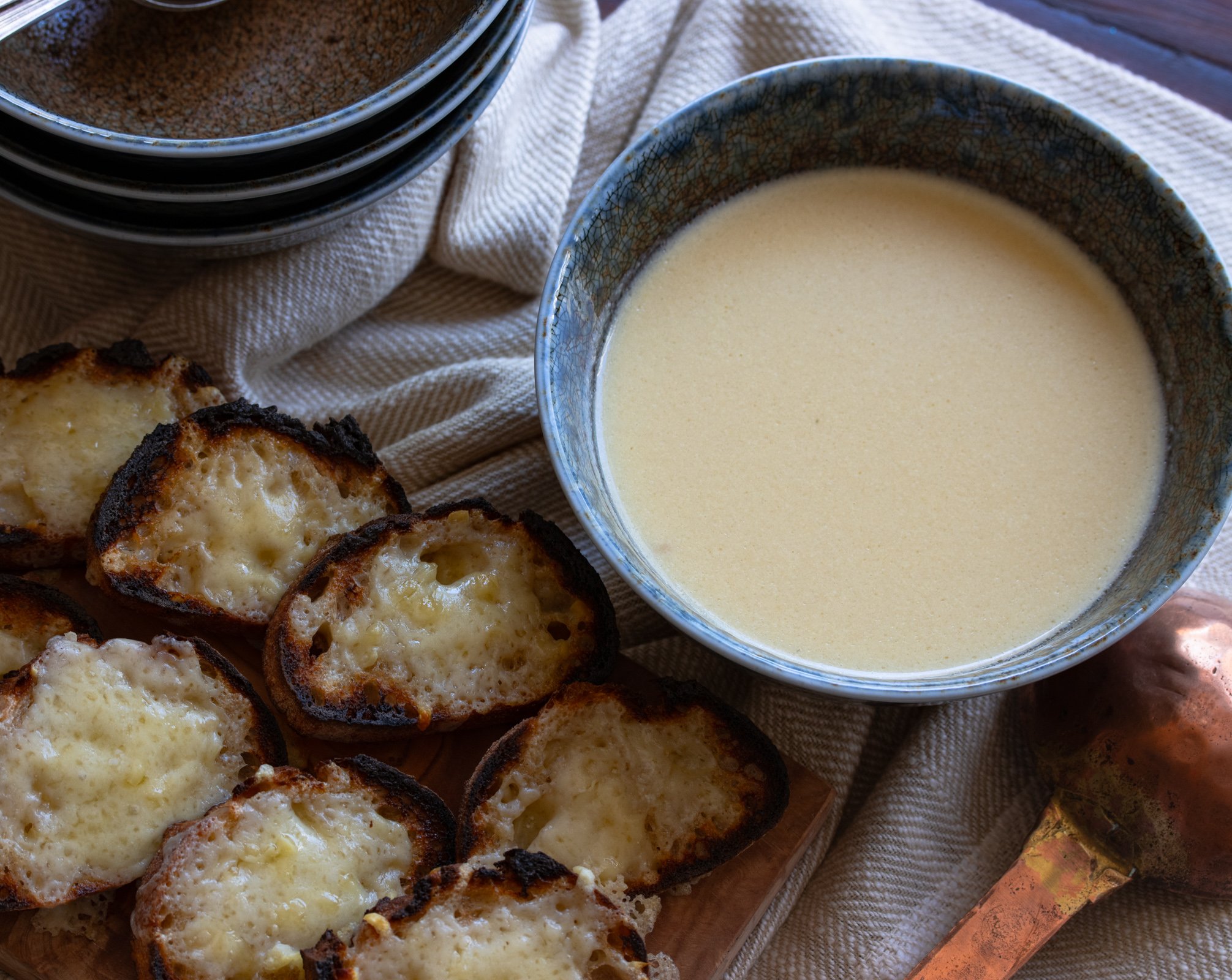 Cheese croutons with garlic soup that is served in blue brown bowls. 