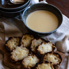 Garlic soup served in blue bowls with cheese croutons by its side.