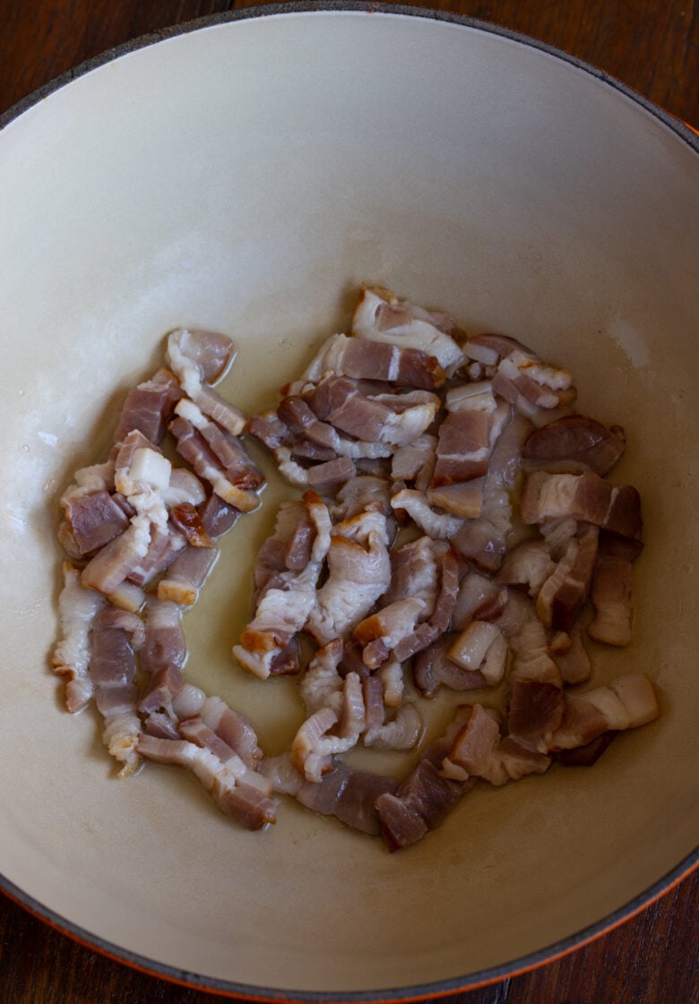 Bacon cooking with the oil in a bottom heavy saucepan.