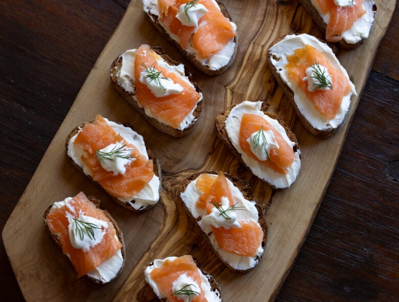 Salmon appetizers ready to be enjoyed placed on a wooden tray.