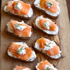 Smoked salmon appetizers on a serving cutting board.