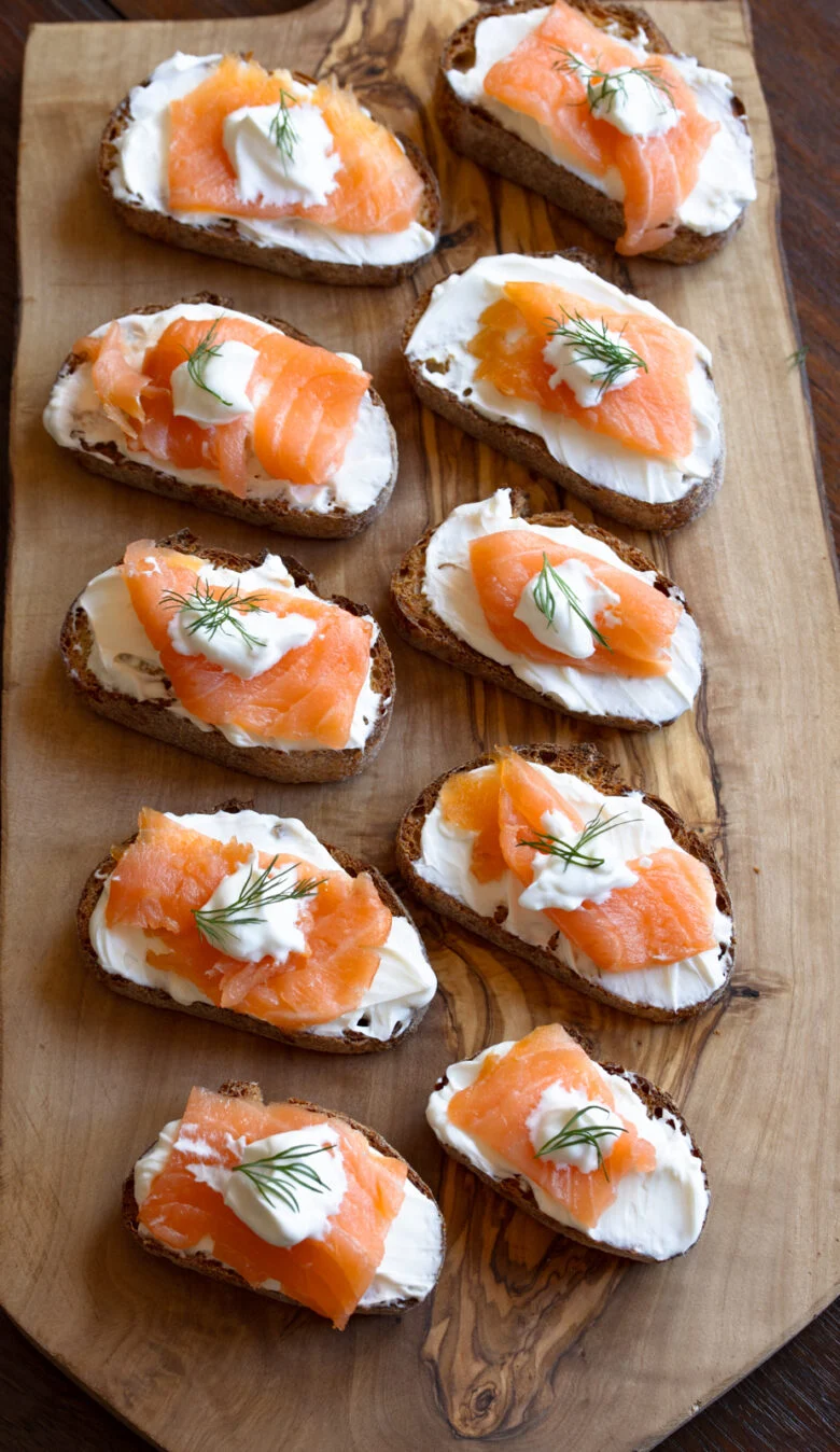 Smoked salmon appetizers on a serving cutting board.
