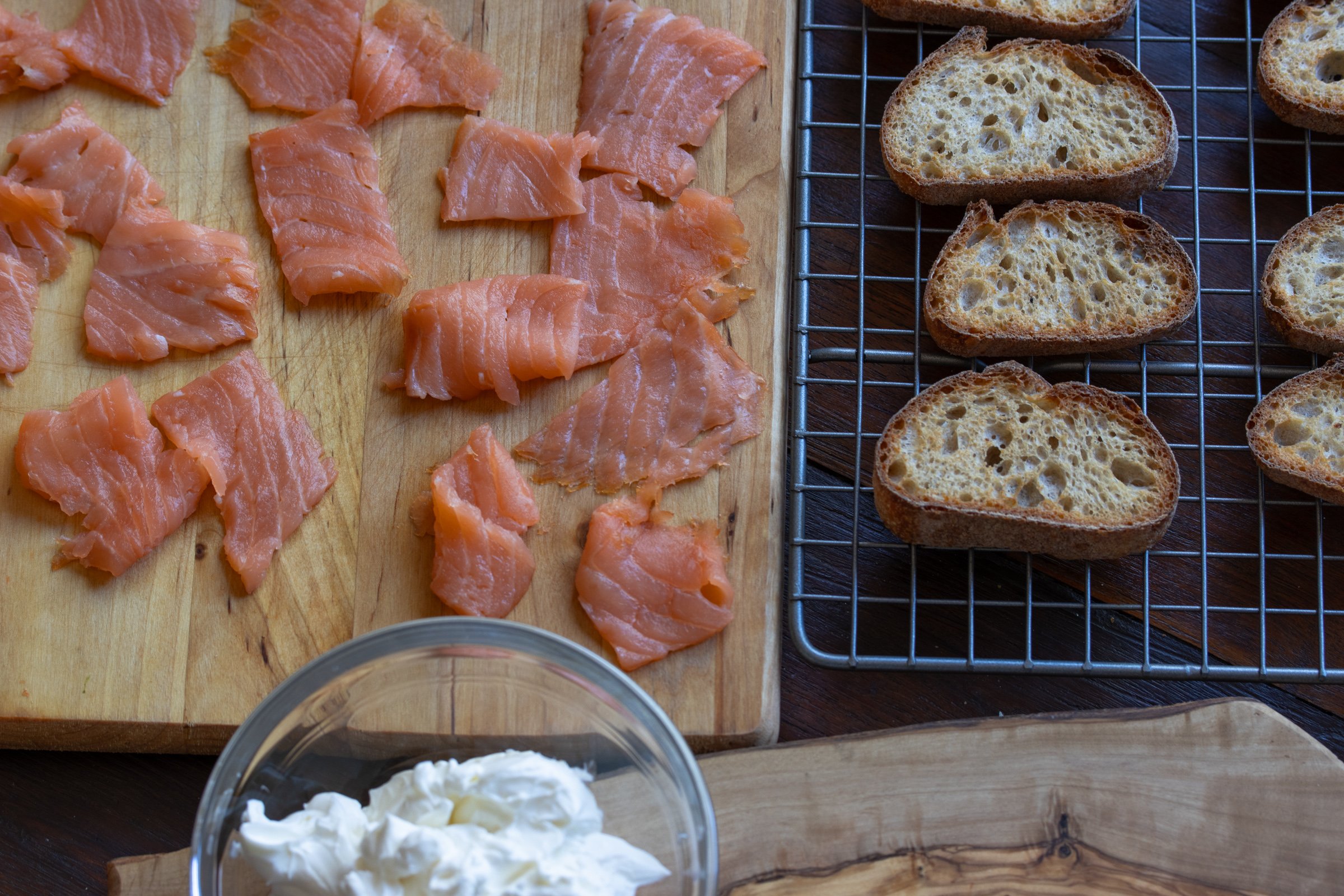 Smoked salmon cut into bite size, bread perfectly toasted on a wire cooling rack.