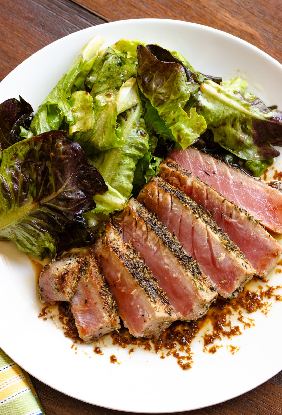 Grilled tuna with salad alongside served on a white plate.