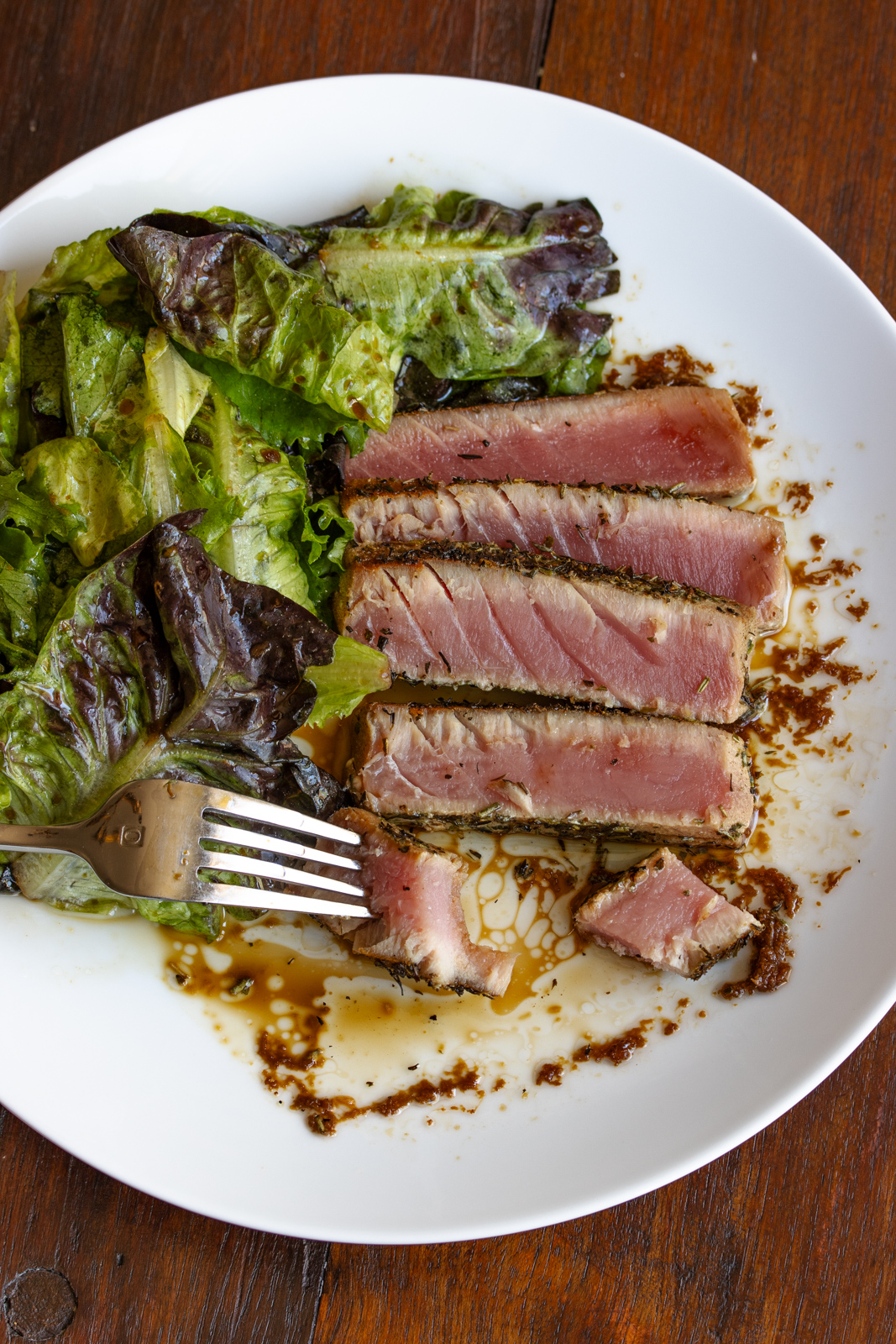 Grilled tuna on a white plate with a piece on a fork.
