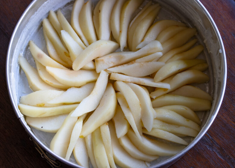 Pear slices arranged in a circular pattern in the buttered springform pan.