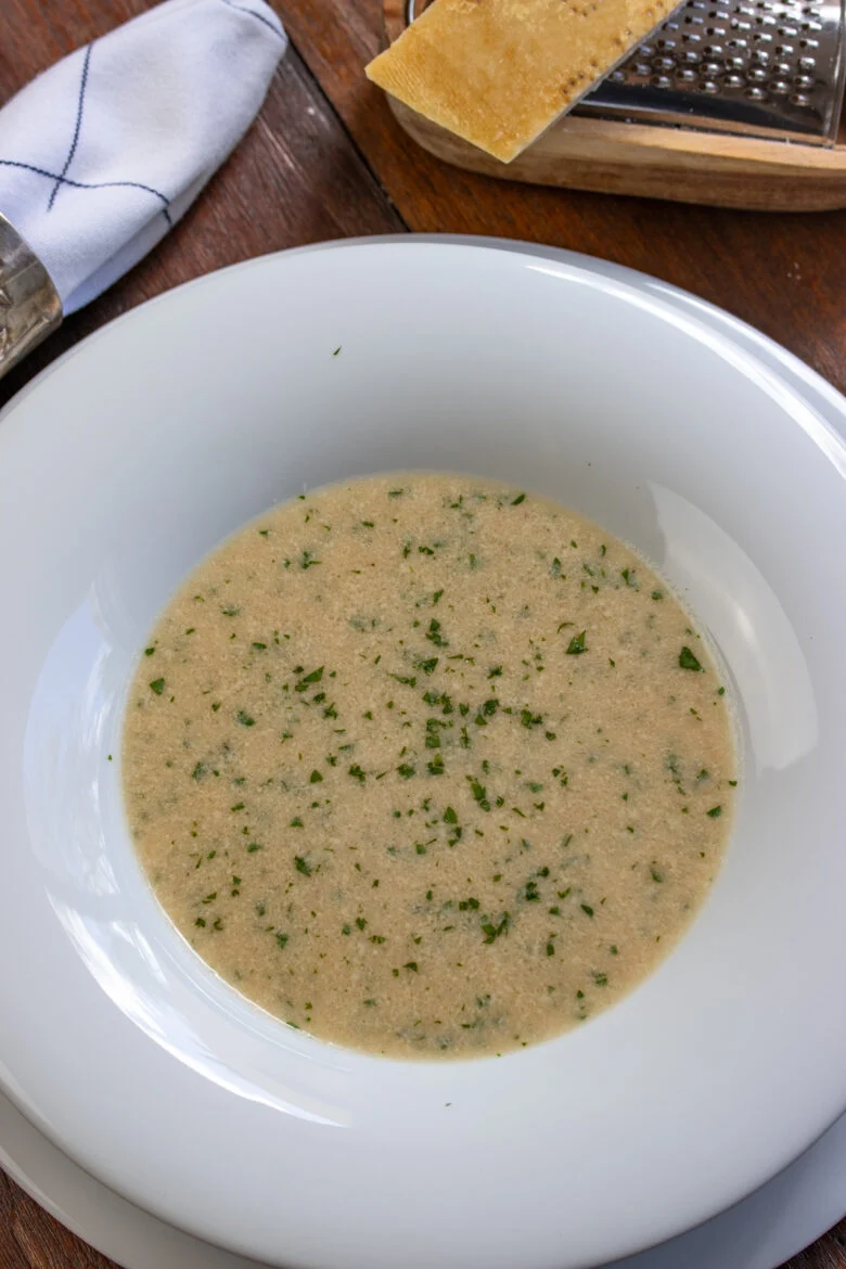 Stracciatella soup served in a white soup plate. 