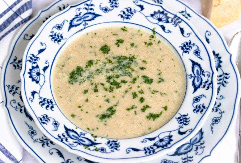 Stracciatella soup served in a white and blue pattern soup dish. 