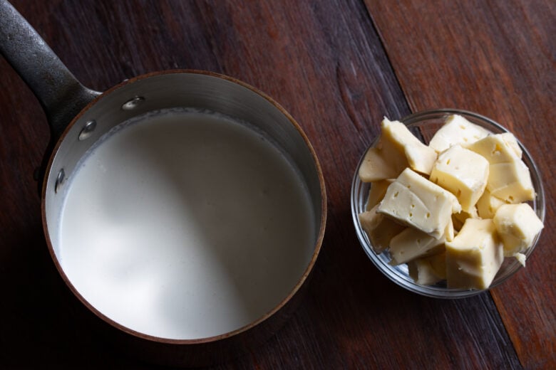 Heavy cream in a pan and sliced French brie cheese.