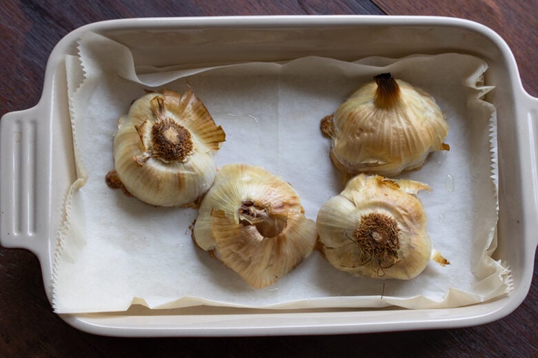 Garlic fully roasted in a baking dish.