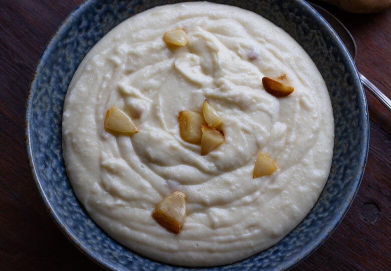 Mashed potatoes all done and served with intact roasting garlic cloves.