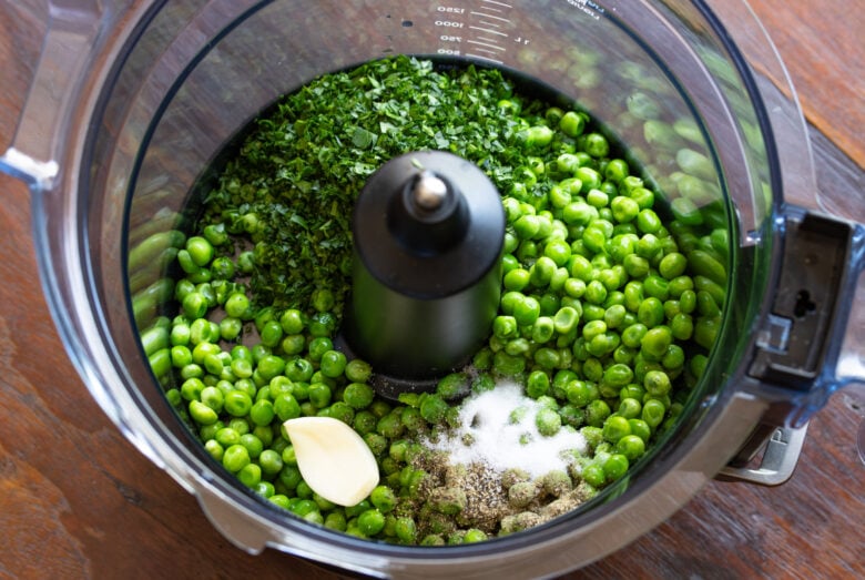 Thawed peas, garlic, salt, pepper. and parsley are placed in a food processor to puree.
