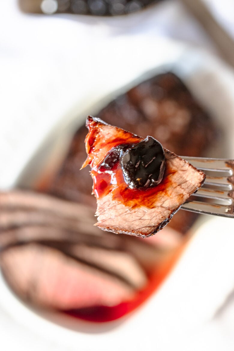 A bite of London broil on a fork with the glaze.