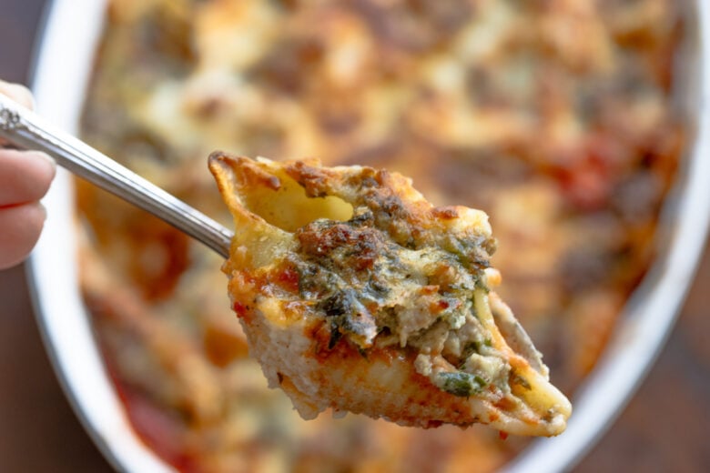 A forkful close up of a stuffed shell with meat ricotta filling