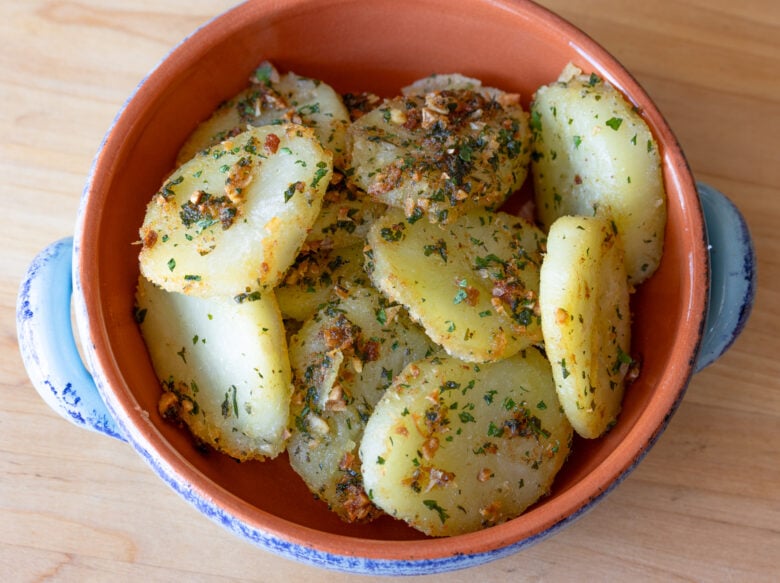 Garlic butter potatoes served in a small terracotta pan. 