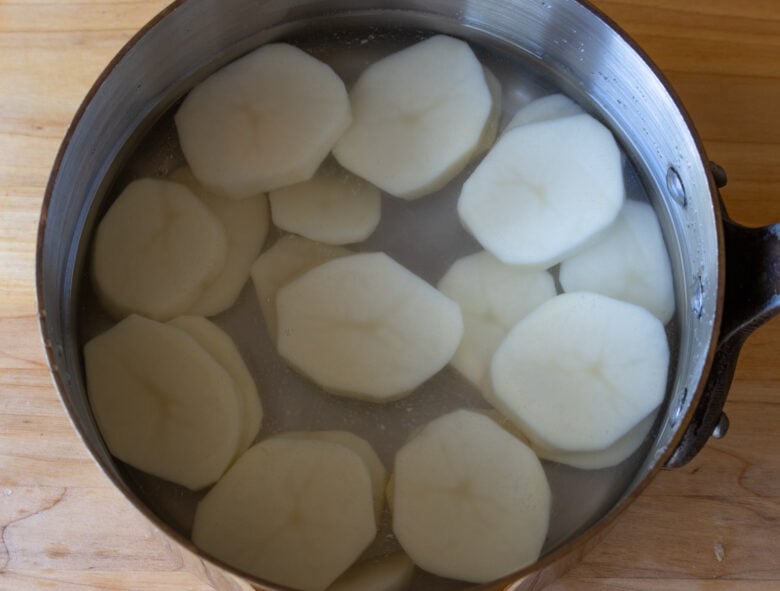 Potatoes rounds in cold salted water ready to be parboiled.