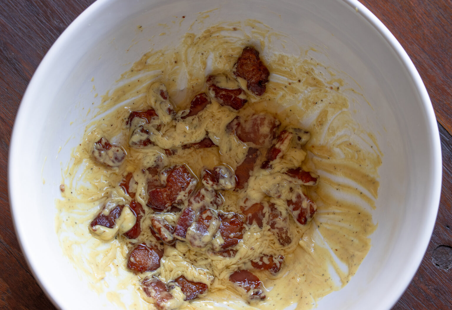 Add half of the bacon with bacon rendering to the mustard dressing.