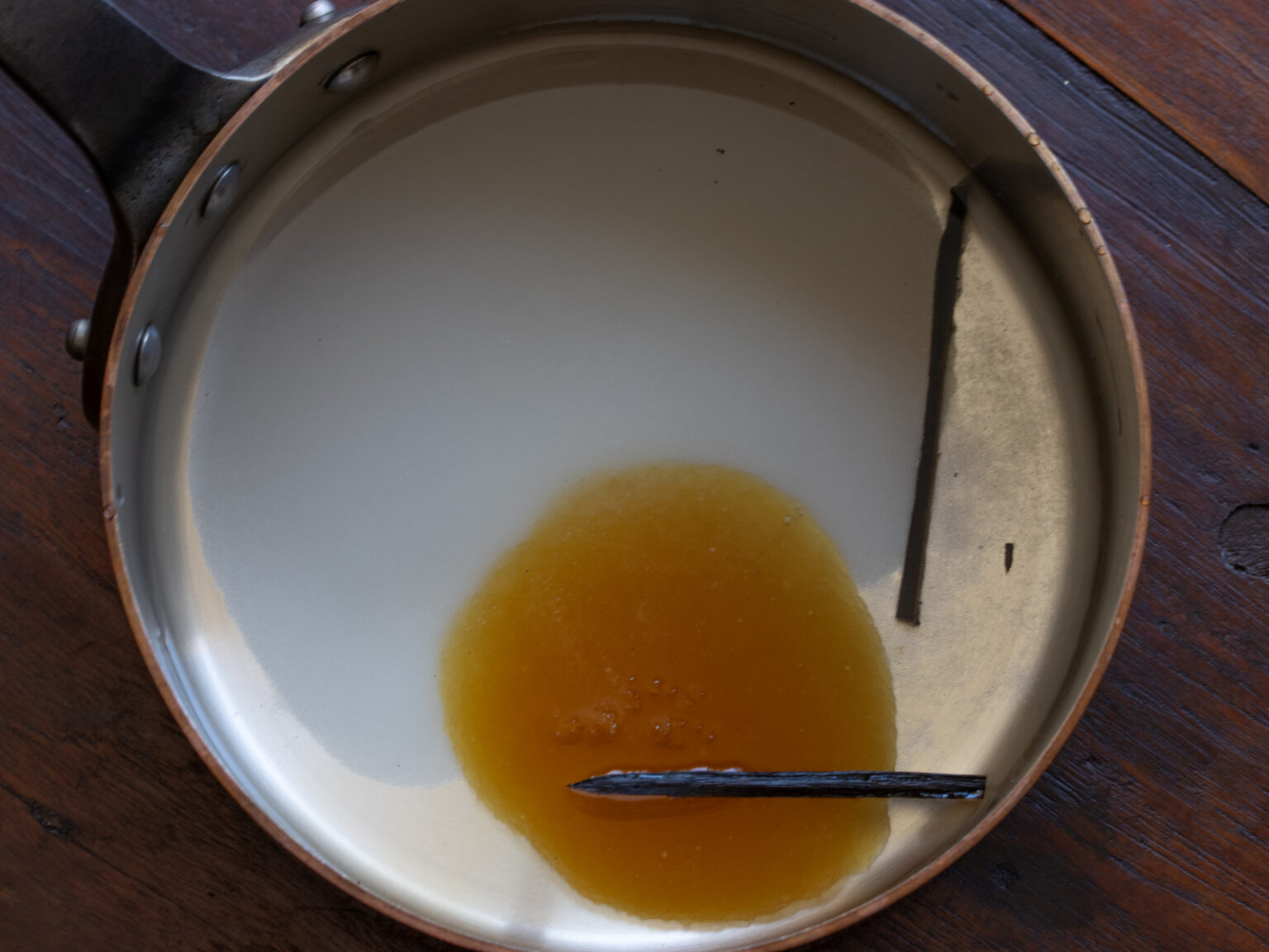 Water, honey, sugar and vanilla bean placed in a sauce pan.