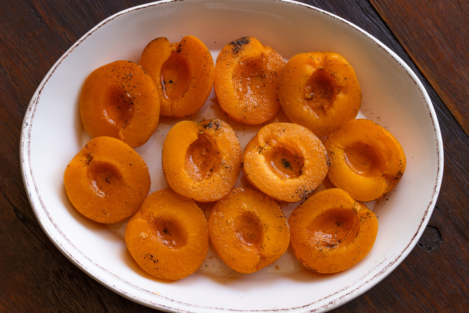 Softened apricots are placed on a white serving dish with borders to hold the sauce.