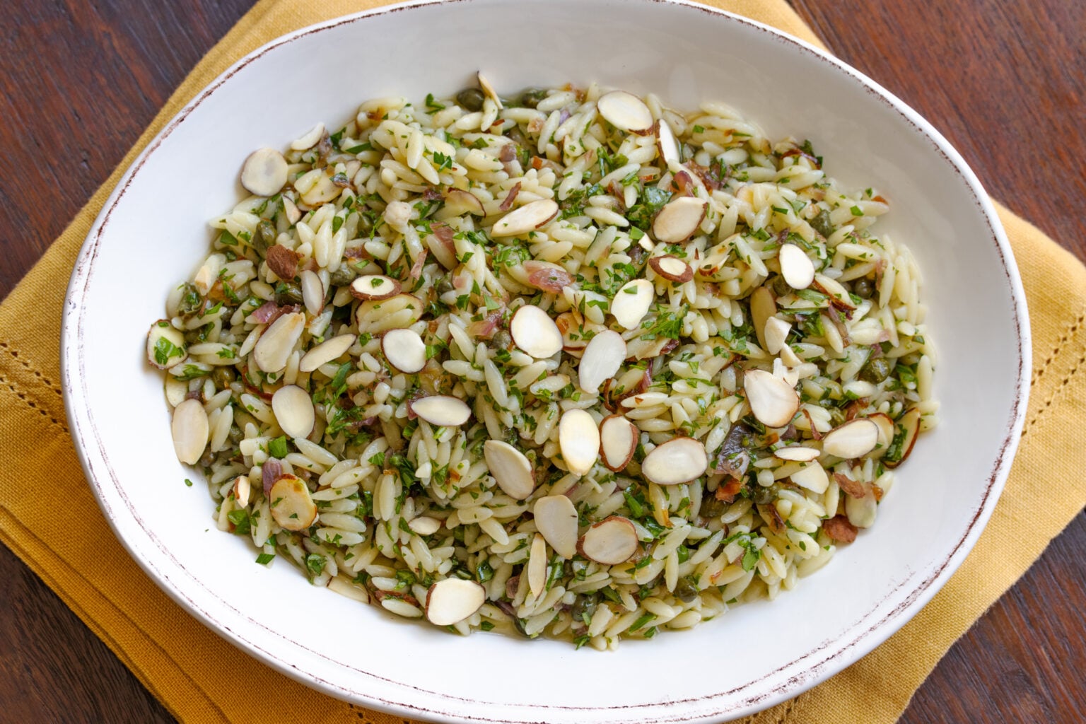 Finished orzo pasta salad served in an oval serving dish.