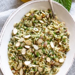 Mediterranean orzo pasta salad with lemon and herbs served in an oval cream color dish.