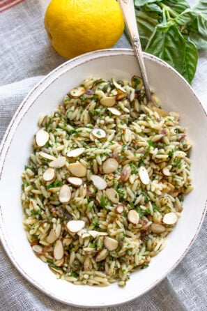 Mediterranean orzo pasta salad with lemon and herbs served in an oval cream color dish.