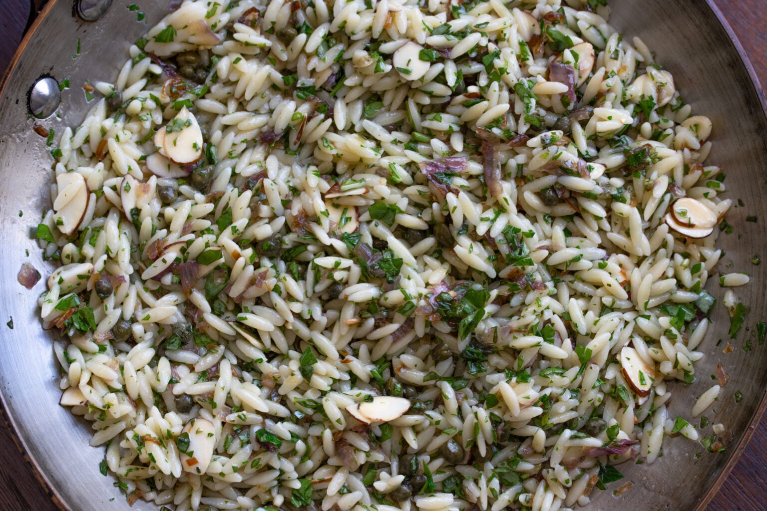 Orzo pasta added with the basil, parsley and half of the alsond slices, to the skillet. 