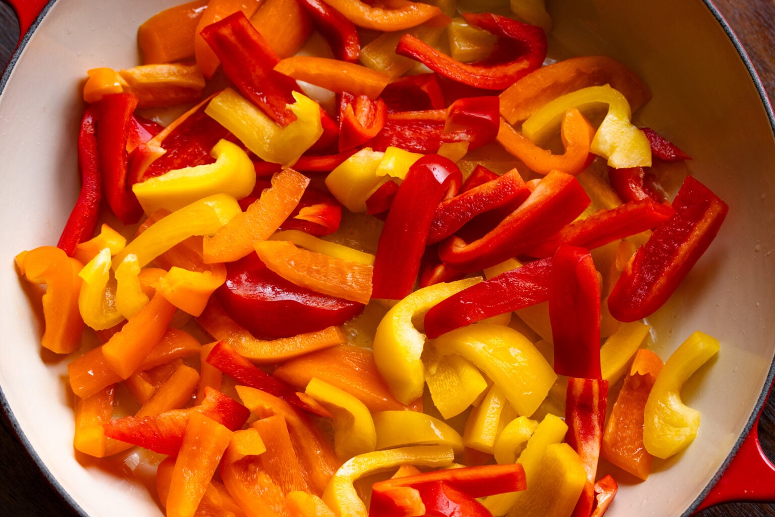 Raw bell peppers chunks added to the skillet with the oil.