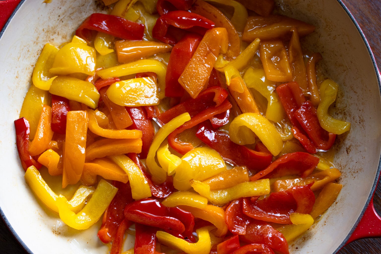 The bell peppers starting to soften during the cooking process.