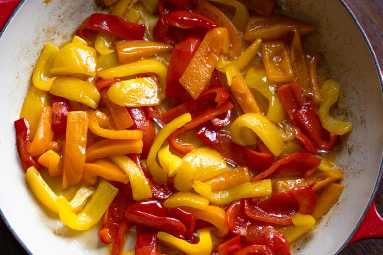 The bell peppers starting to soften during the cooking process.
