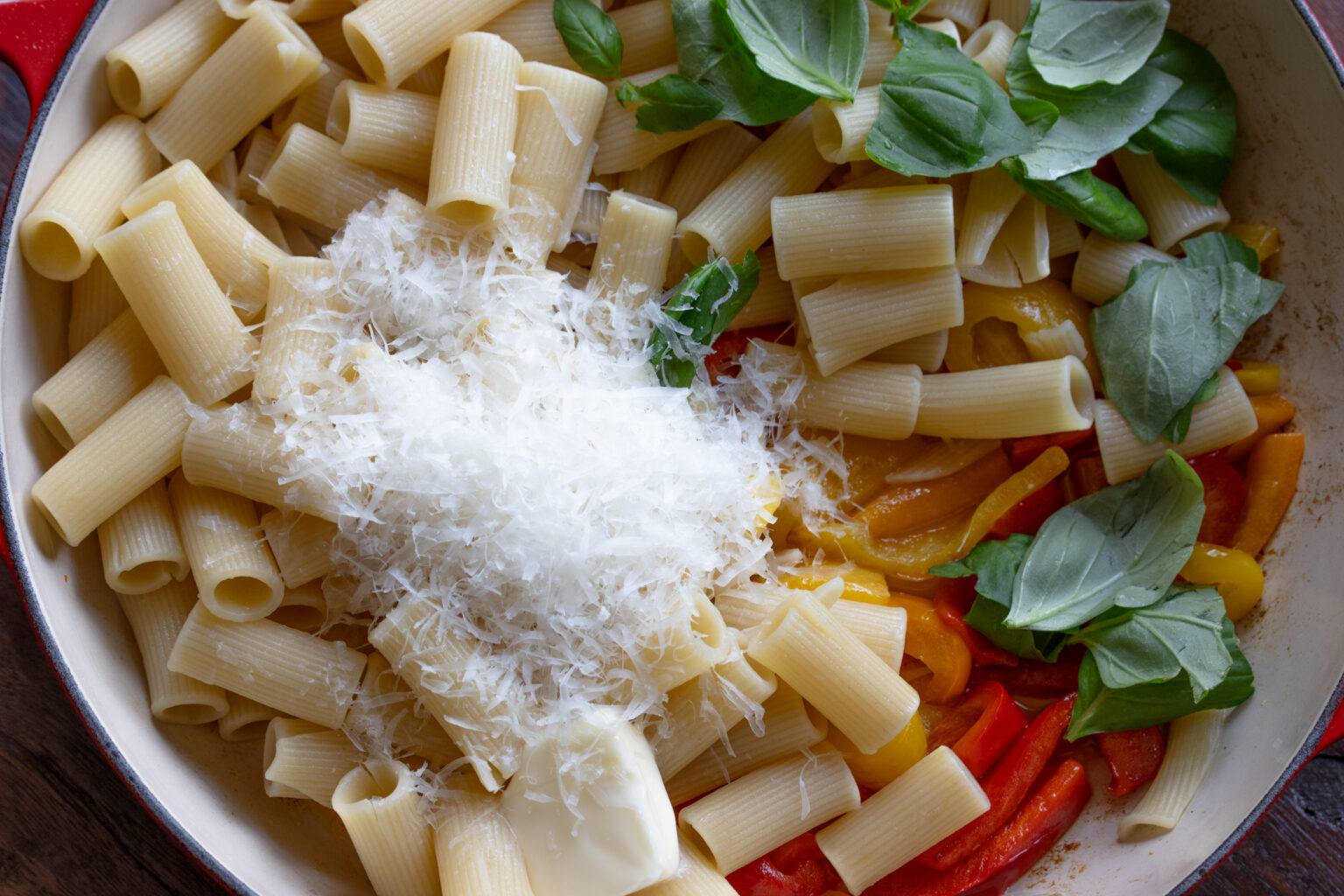 Cooked pasta added to the peppers alongside basil and grated Parmesan cheese. 