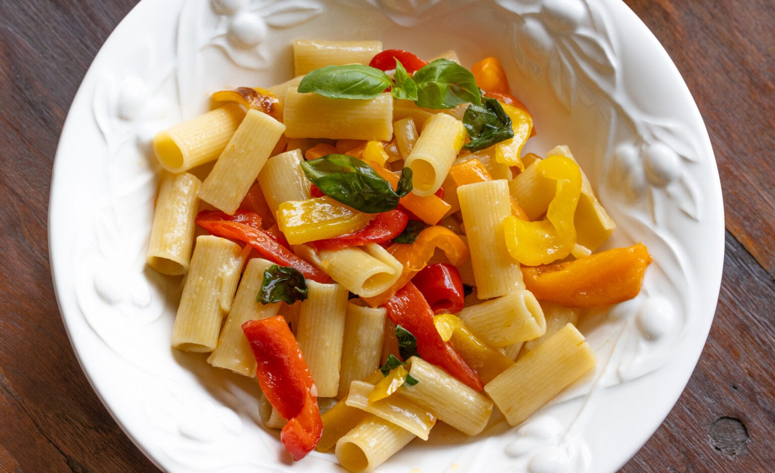 Roasted bell pepper sauce with garlic, basil and rigatoni pasta served in a white pasta dish. 