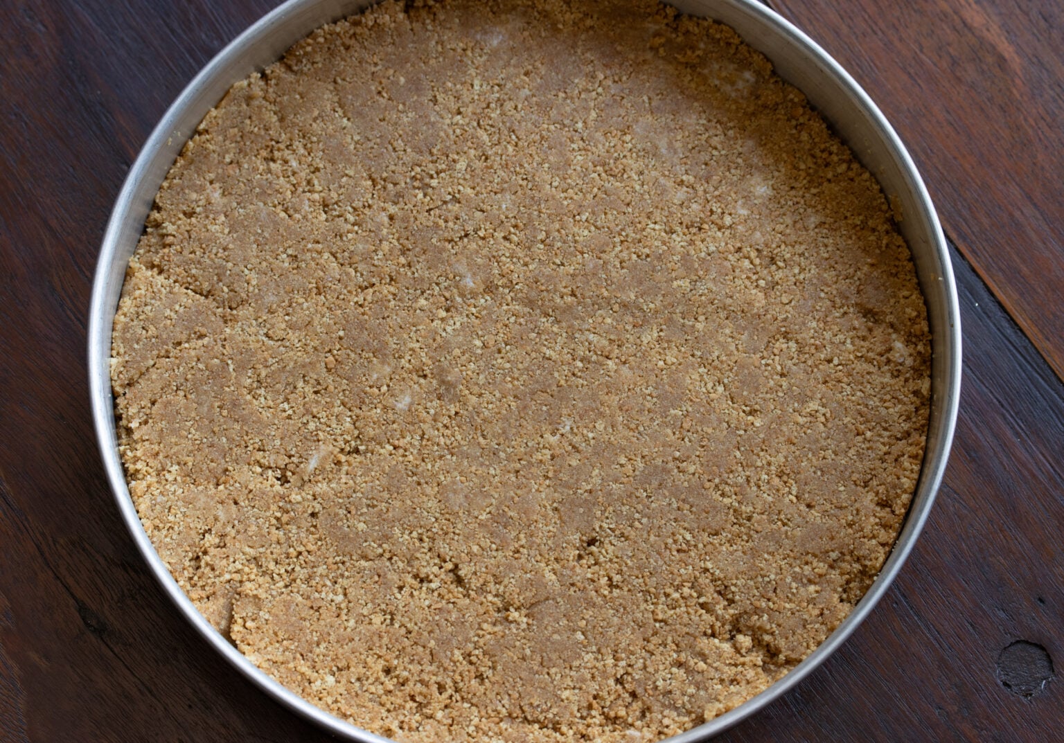 Graham crackers blended with the butter and placed into a round cake mold with removable bottom. 