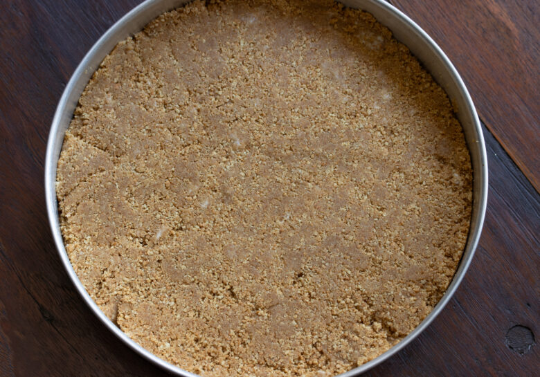 Graham crackers blended with the butter and placed into a round cake mold with removable bottom. 