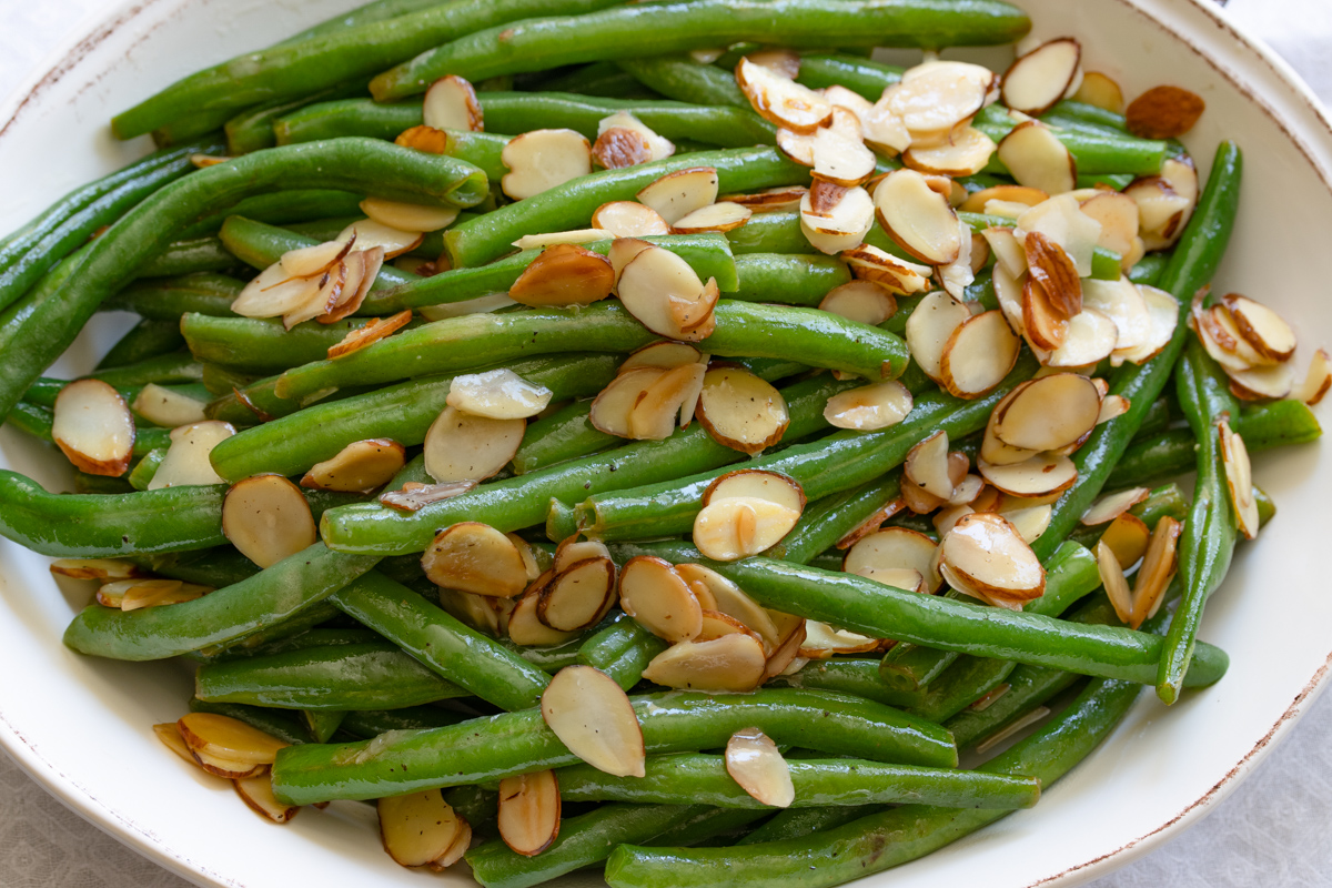 Green bean almondine served in an oval cream color serving plate.
