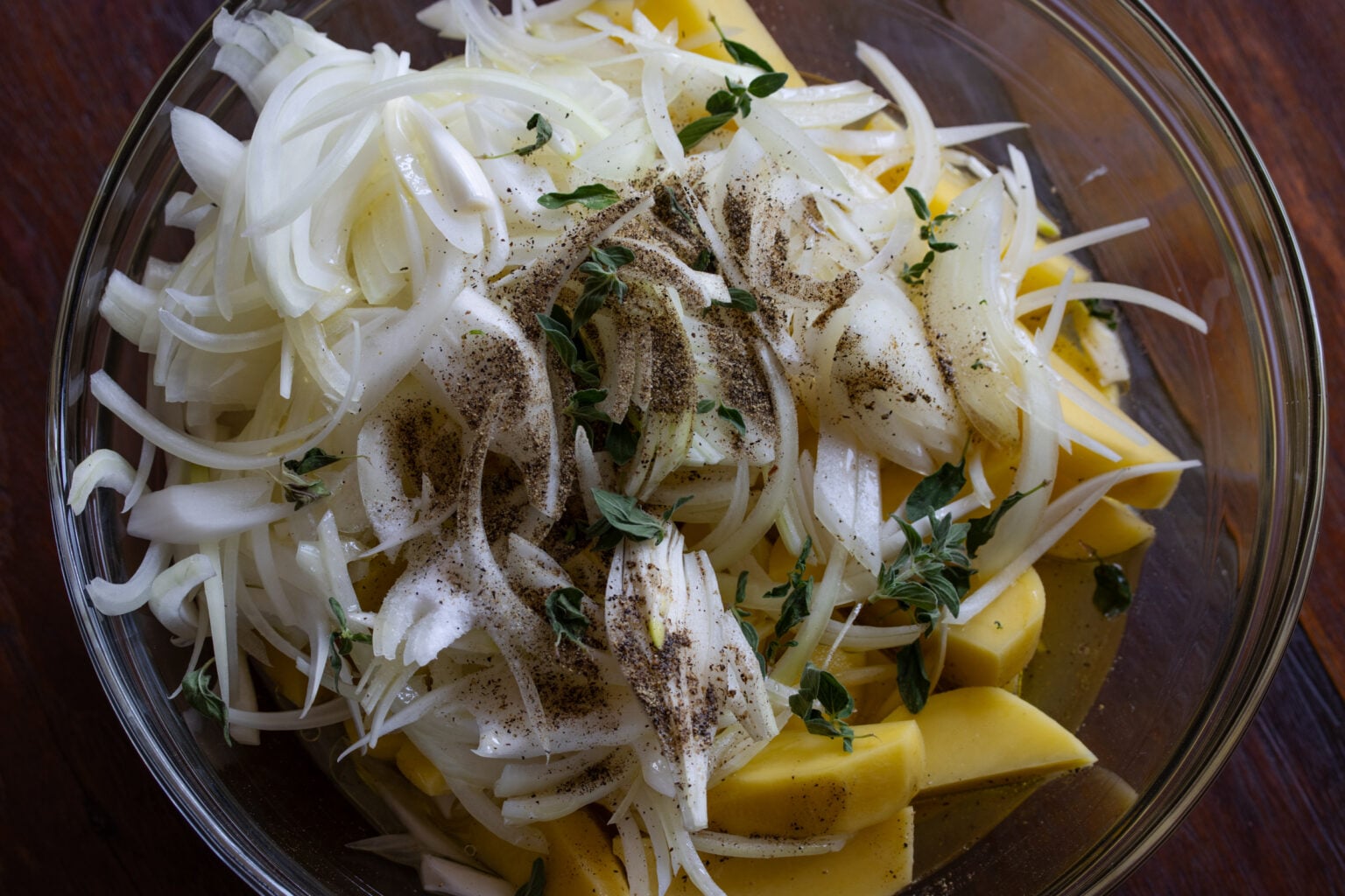 Potatoes, onions, chicken broth, lemon juice and oregano are all mixed together before being placed on the bottom of a Dutch oven.