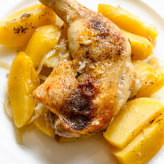Greek lemon chicken and potatoes served on a cream white plate.