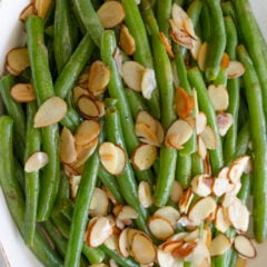 Green bean almondine served on ahwhite oval plate.